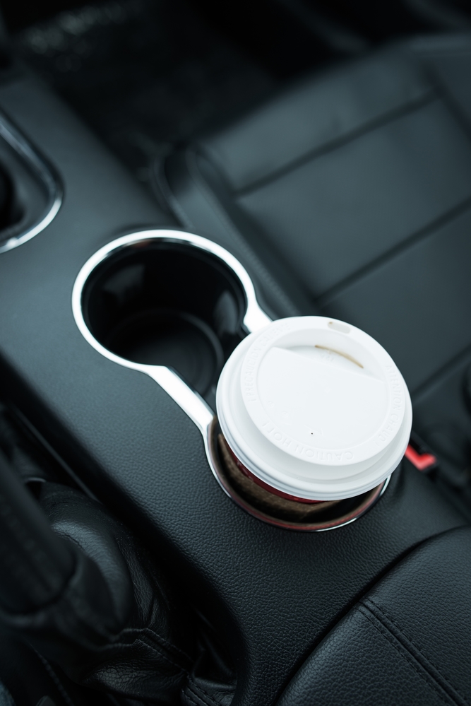 Coffee Drinking While Driving. Single Paper Coffee Cup Inside Car Cup Holder.